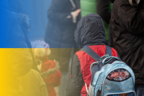 Lapsi reppu selässä ja ukrainan lippu. 