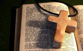 kuvassa avattu Raamattu, jonka päällä puinen risti
