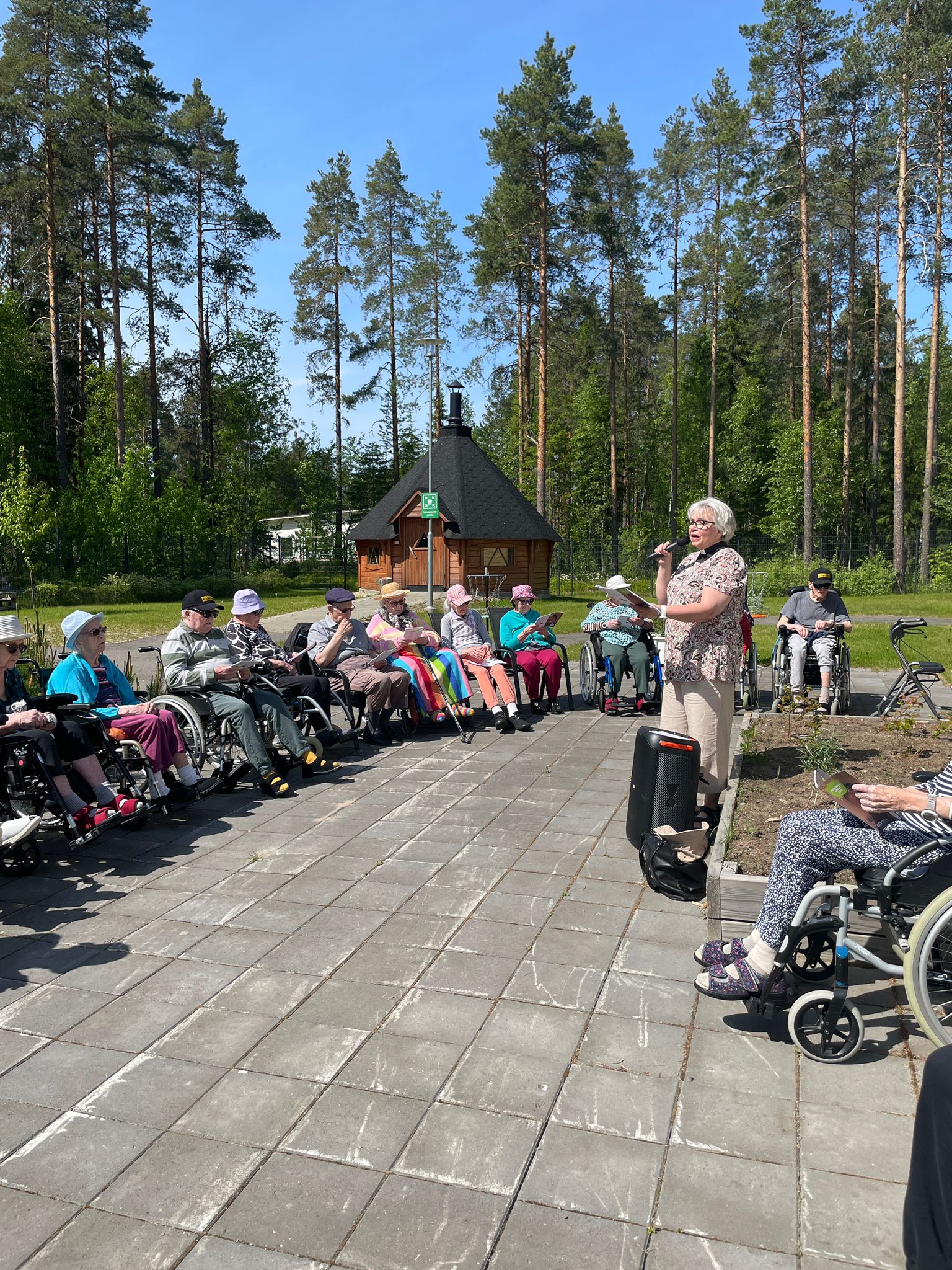 Hoivakodin asukkaita ulkona kuulemassa hartautta jota sairaalapastori pitää.
