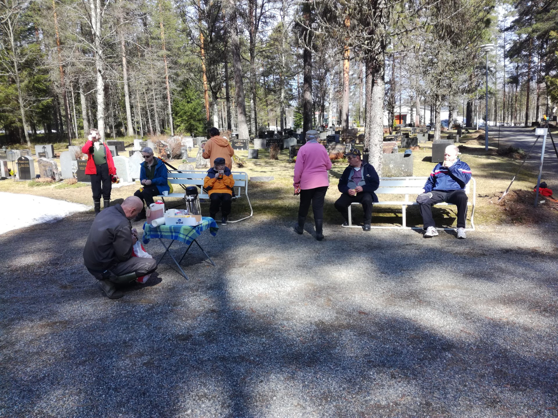 Kangaslammin hautausmaan siivoustalkoiden työväkeä kahvitauolla istumassa ja juttelemassa.