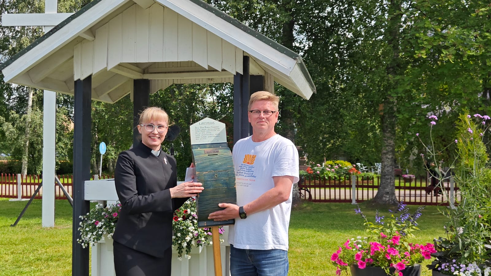 Mies ja nainen pitelevät käsissään herättäjuhlien puista lähetyslipasta.