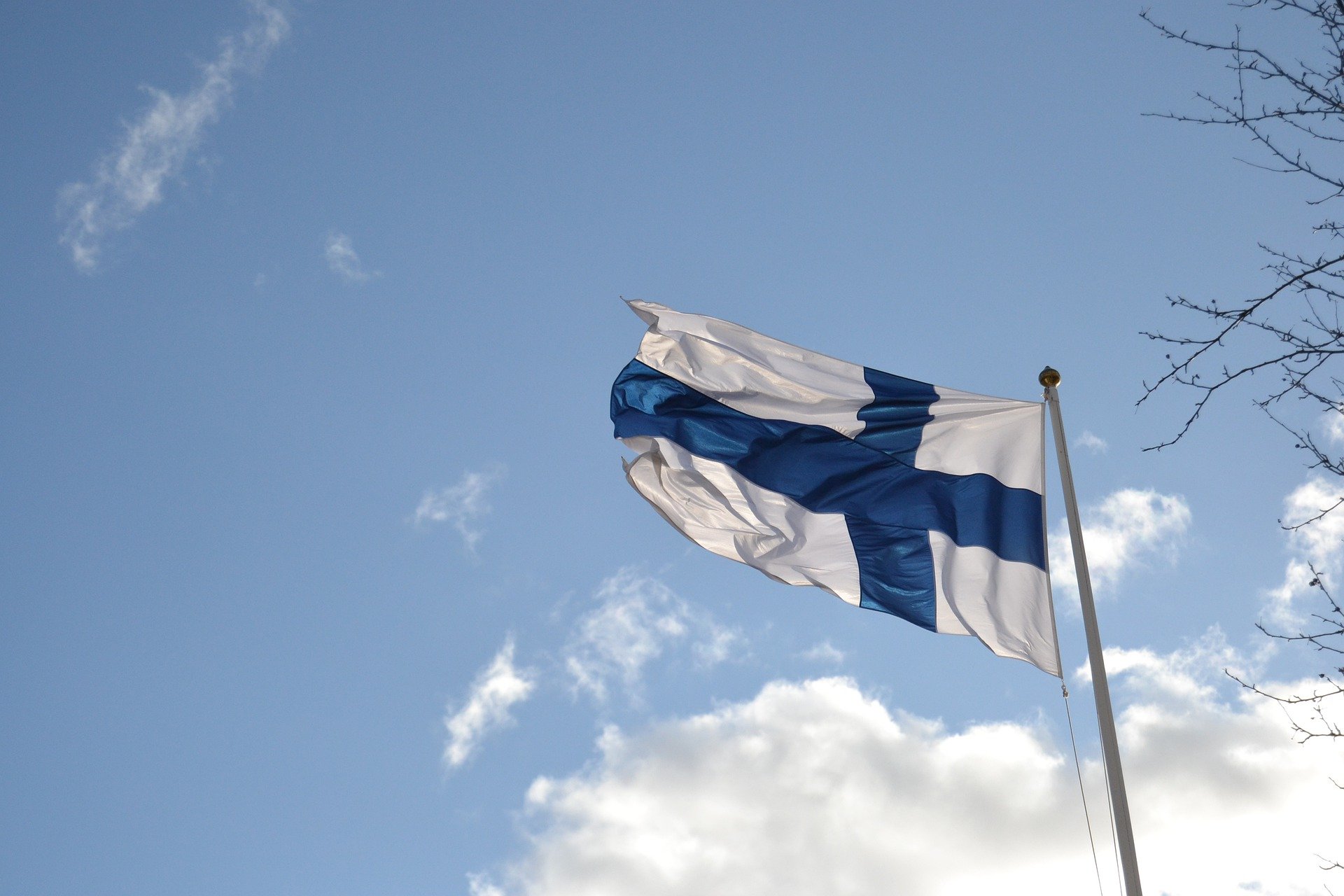 Kuvassa hulmuava suomen lippu taivasta vasten.