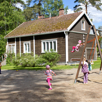 Metsäpirtin kerhotila ulkoa päin. Pihamaalla leikkiviä lapsia.