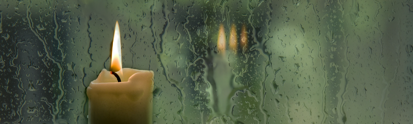 Kynttilä ikkunalla, sataa, vesi valuu ikkunoissa.