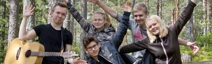 Nuoria yhteiskuvassa, pappi kitaran kanssa isosten yhdessä.