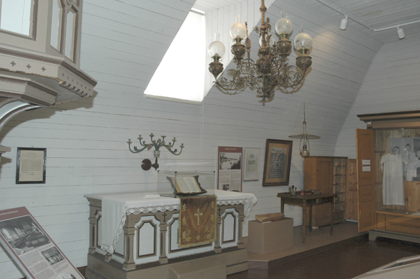 Kuvassa kirkkomuseon vanhaa esineistöä ja kattokruunu.
